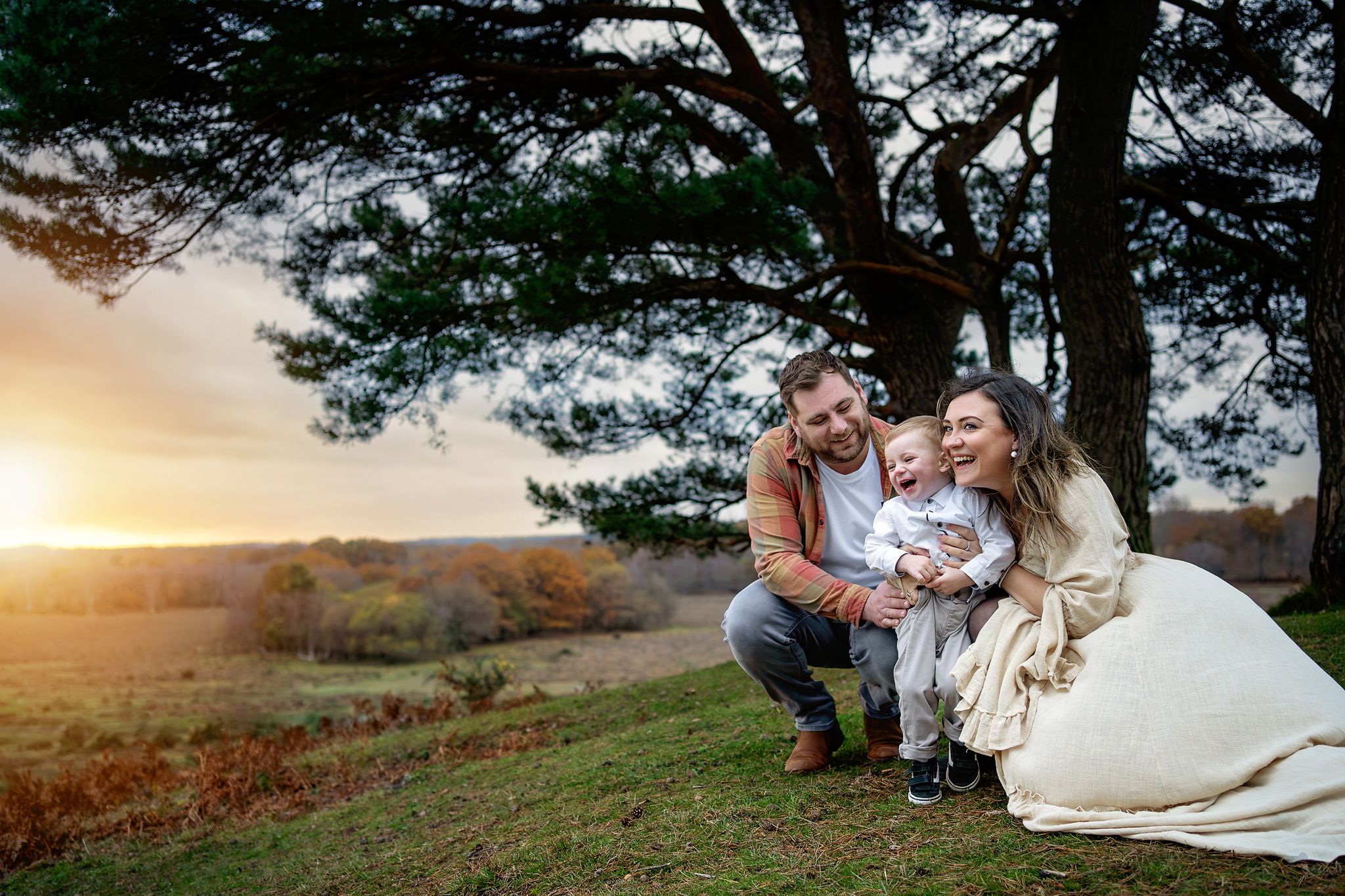 Parents holding their child, while watching a beautiful sunset in The New Forest, UK.