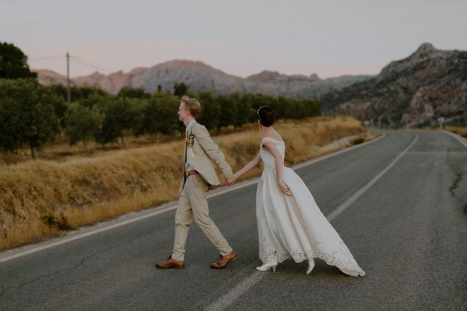 A romantic wedding couple poses on an empty mountain road at sunset. Destination Wedding in Malaga, Spain.