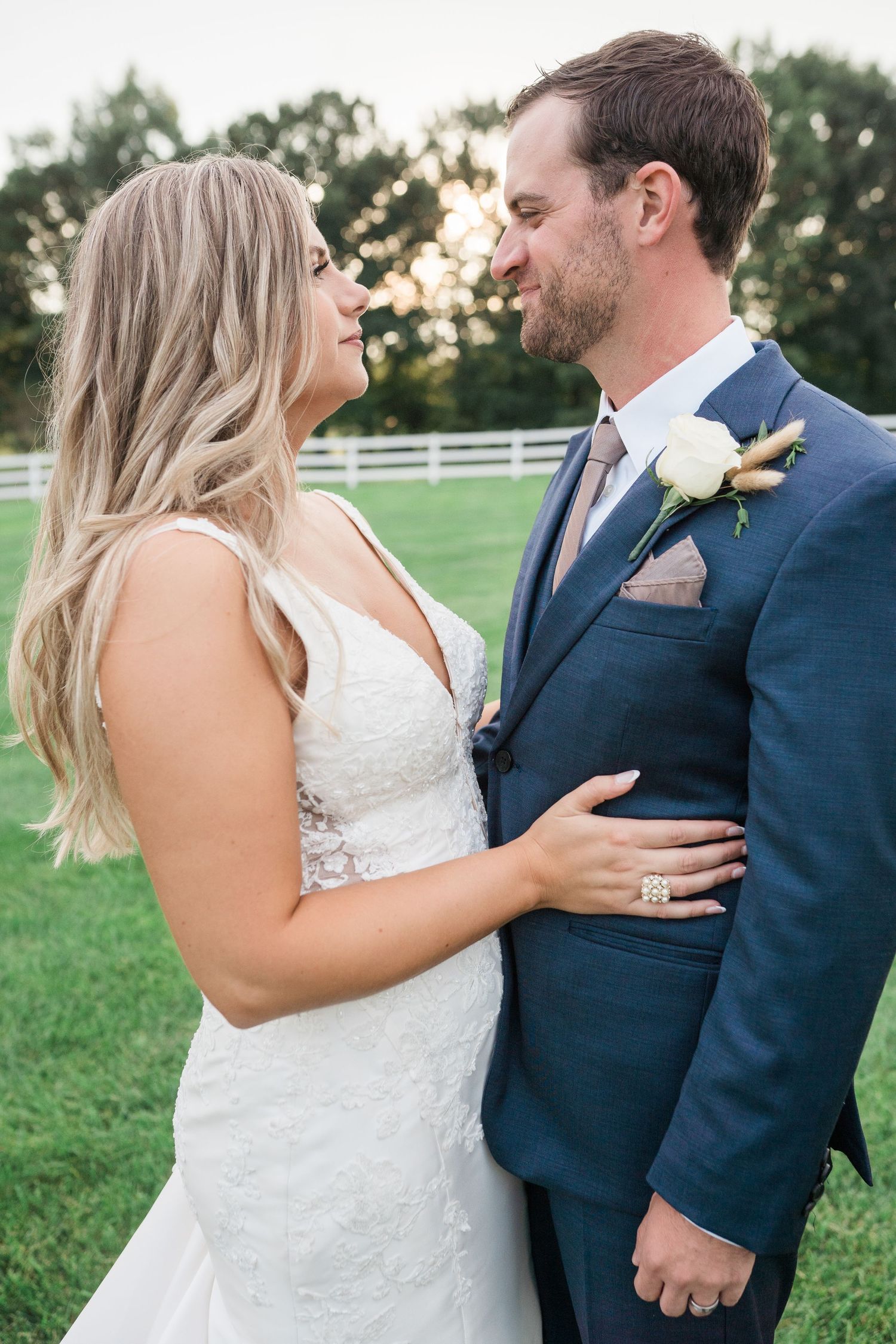 A bride and groom embracing and looking lovingly at each other in a scenic outdoor setting.