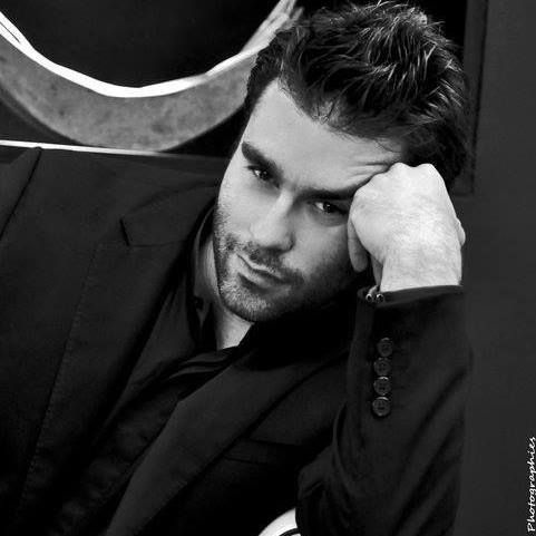 Black and white portrait of a man in suit leaning thoughtfully against a mirror.
