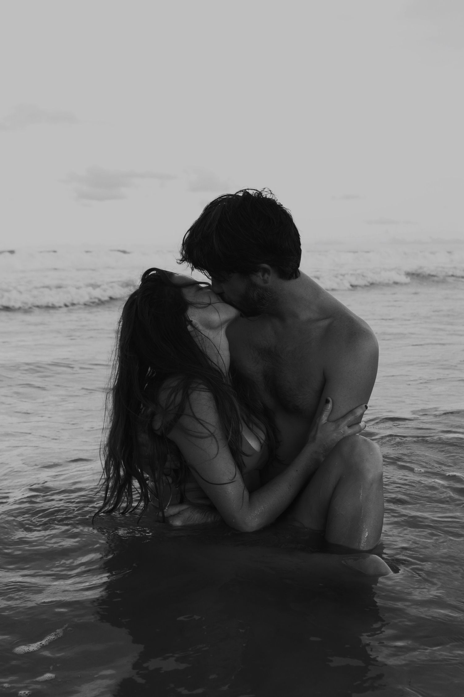 Love story of couple kissing in the waves of the Atlantic ocean