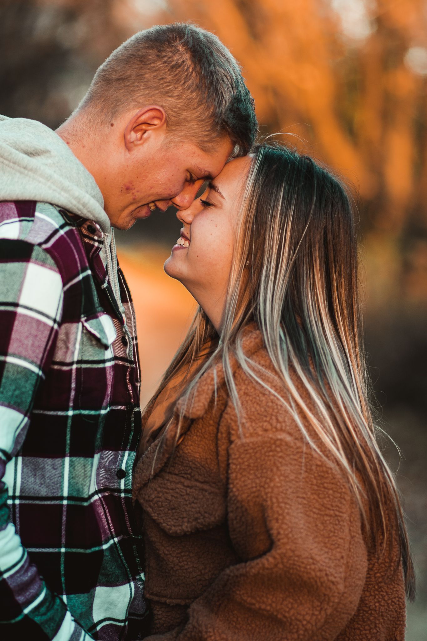 An intimate close-up of a couple sharing a joyful moment in autumn outdoor setting.