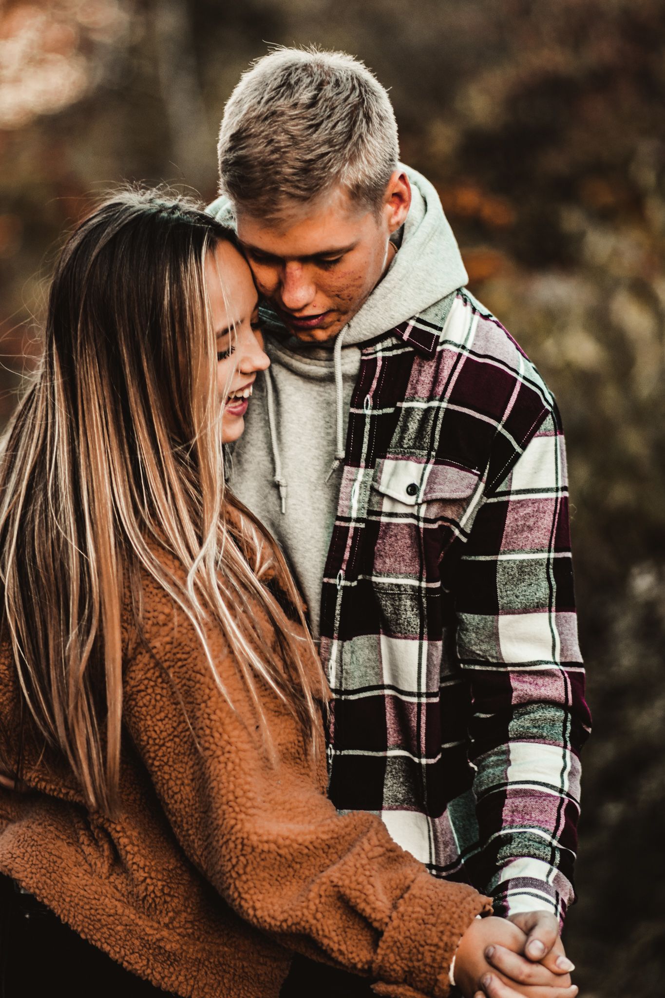 Couple in warm fall clothing sharing loving moment against blurred autumn background.