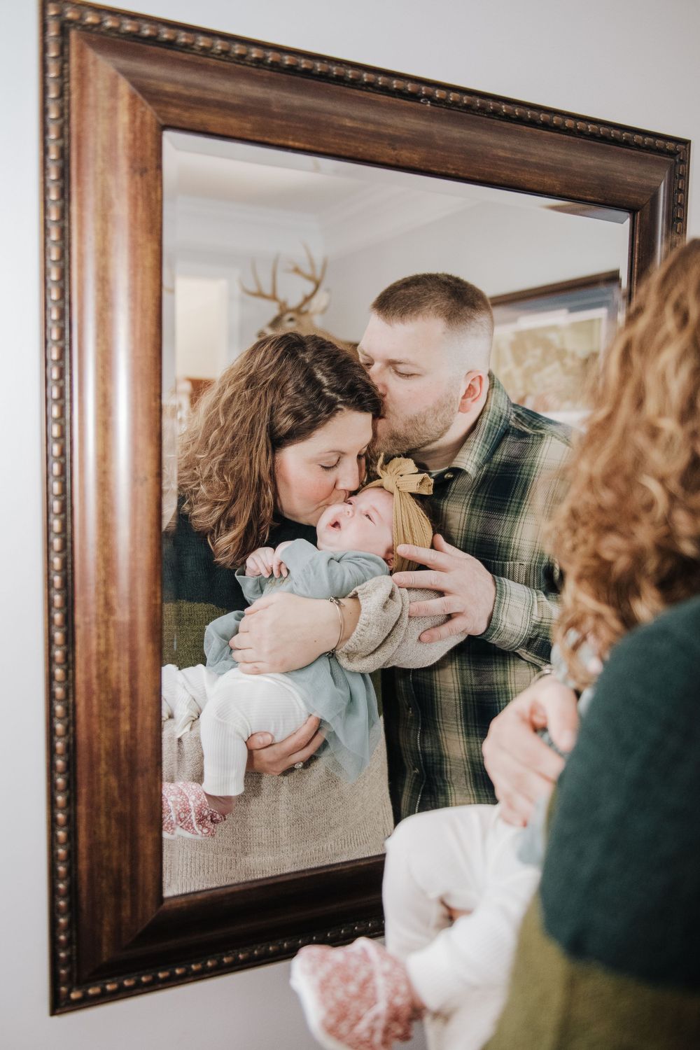 A reflection in an ornate mirror captures a tender family moment.