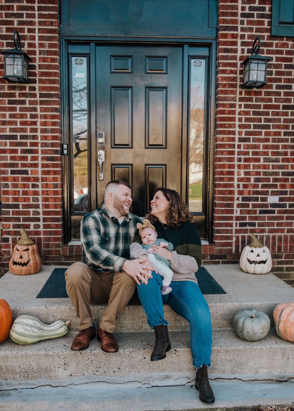Fall themed front porch scene with pumpkin decorations and brick exterior.