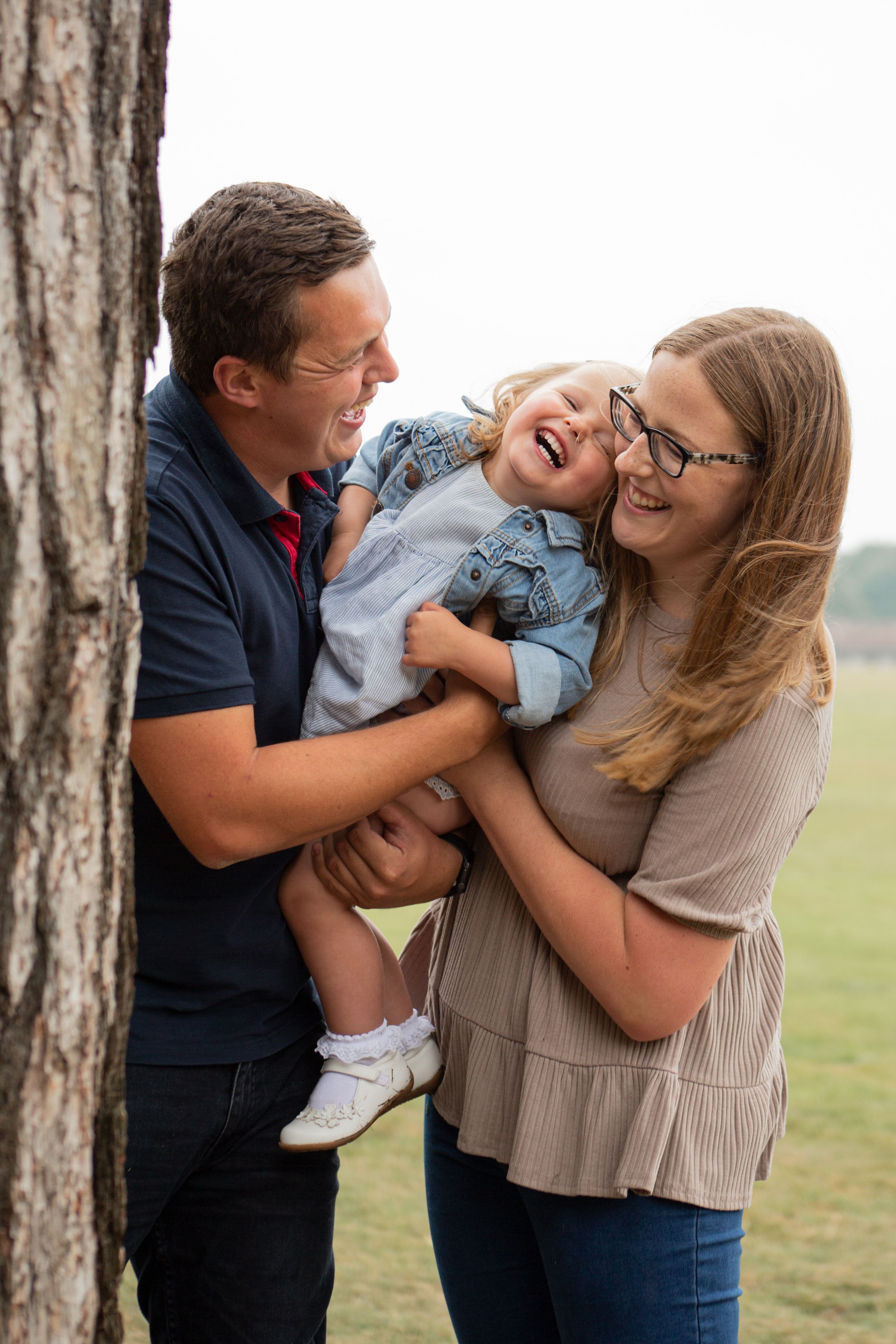 A playful family moment captured by a tree as they share laughter together.