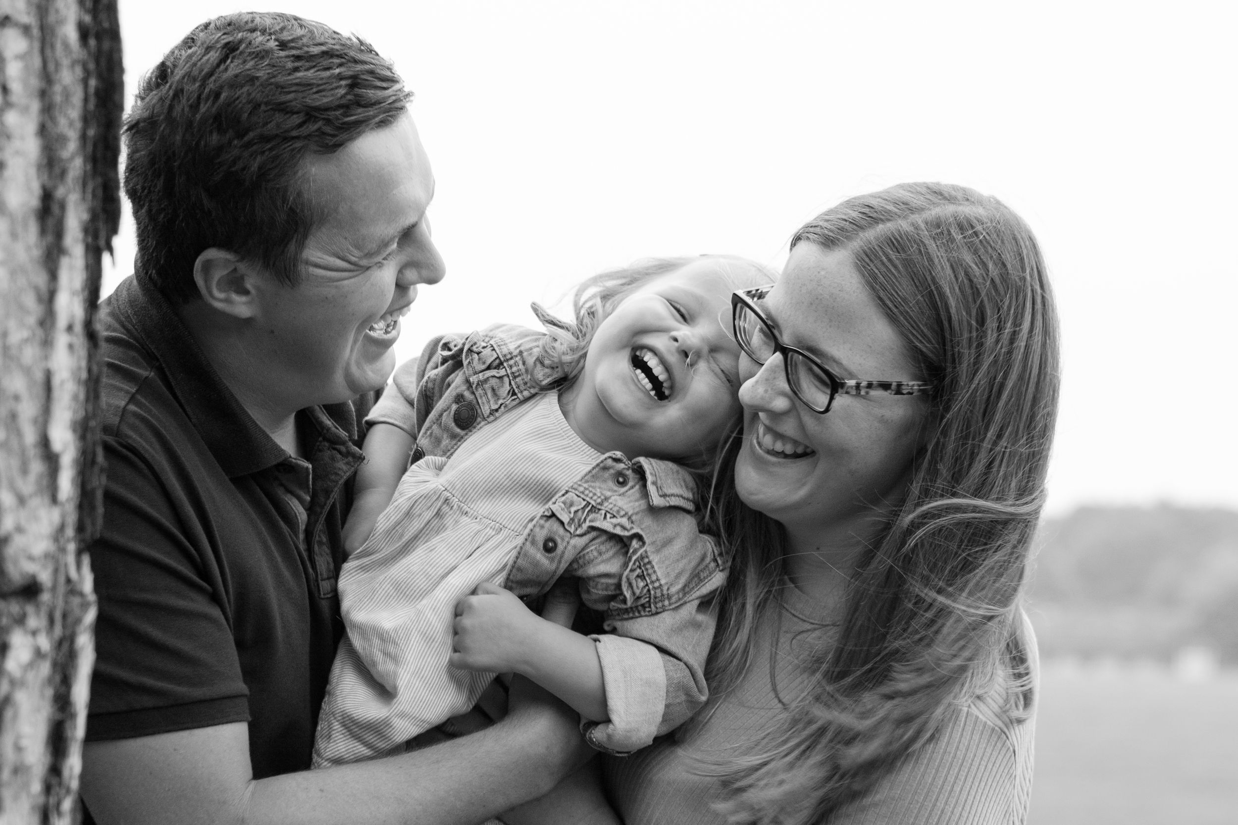 A candid black and white photo captures a family sharing a joyful laugh together.