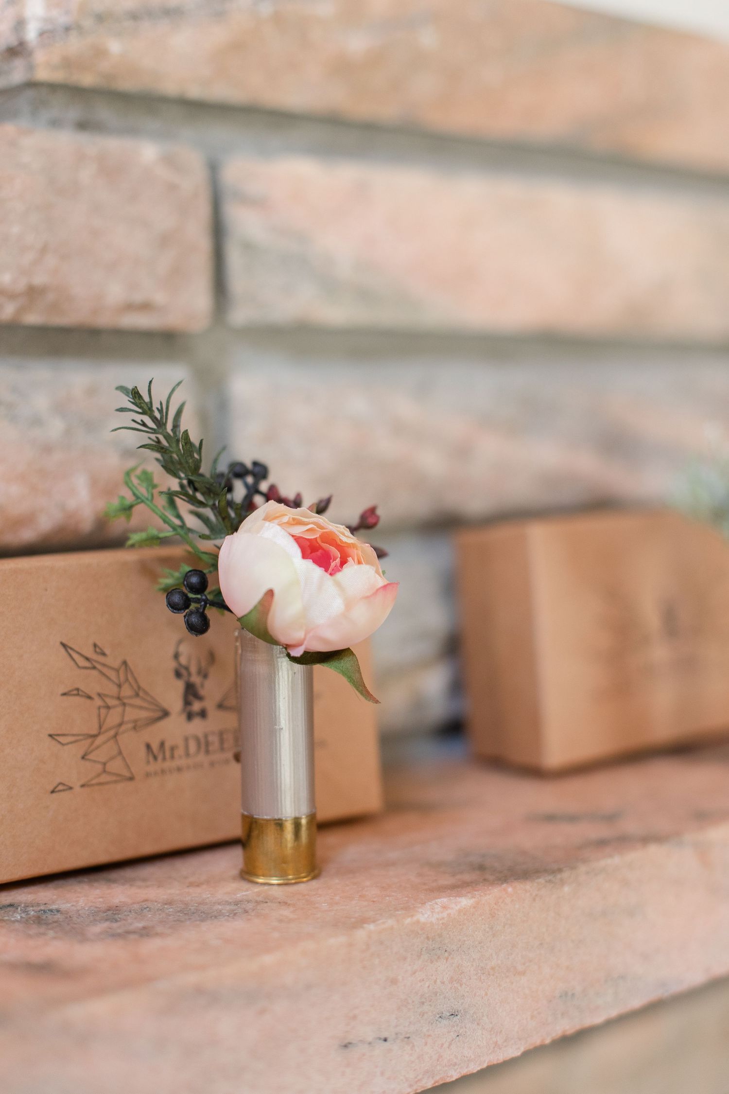 Delicate peach garden roses in small gold vases displayed on brick ledge.