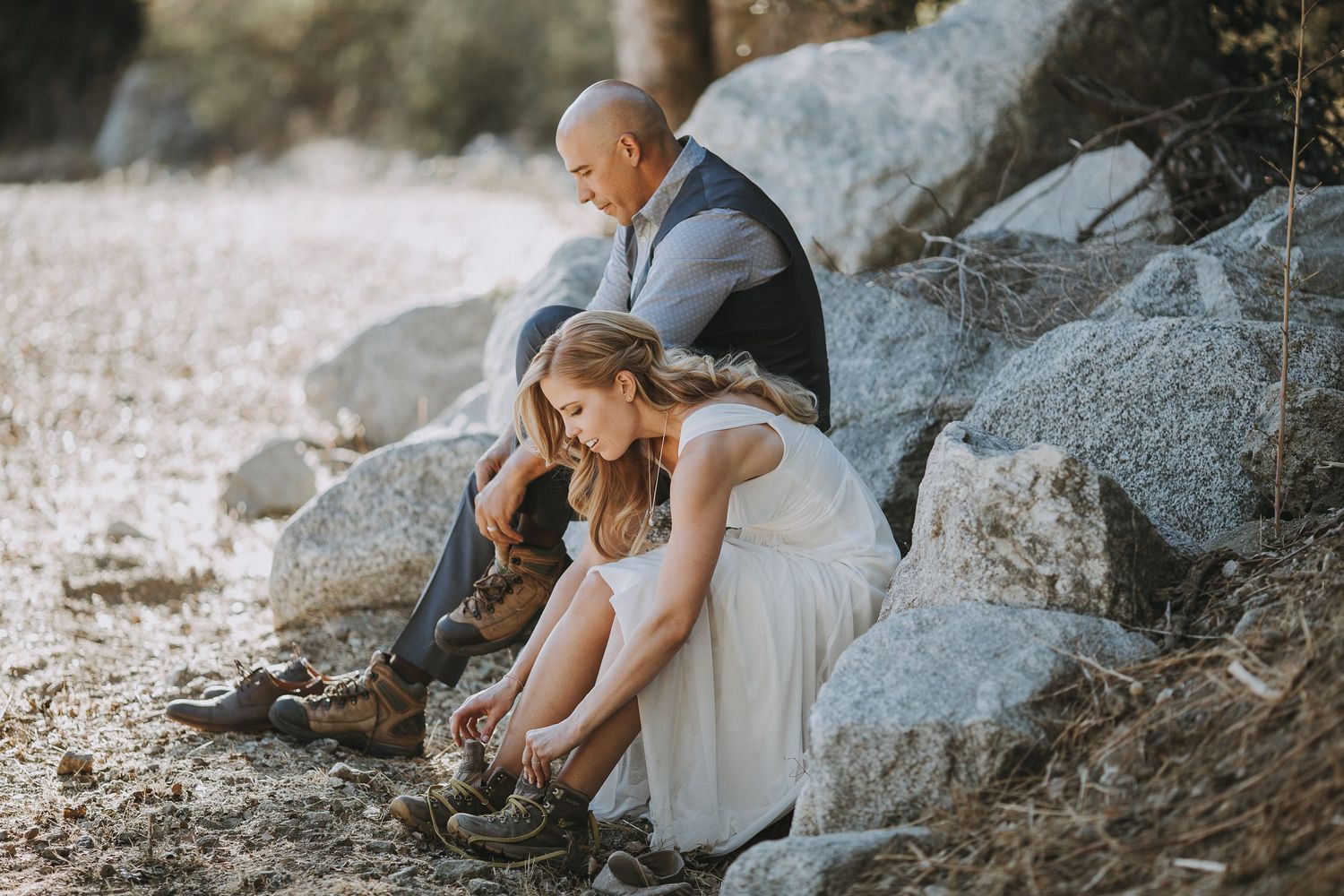 Two people sitting together on coastal rocks in casual attire.