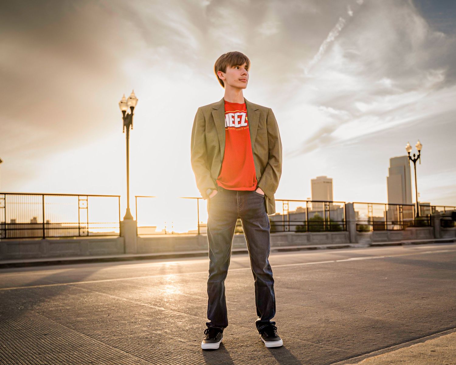Person in casual attire standing on a rooftop parking structure at sunset with city buildings in the background.