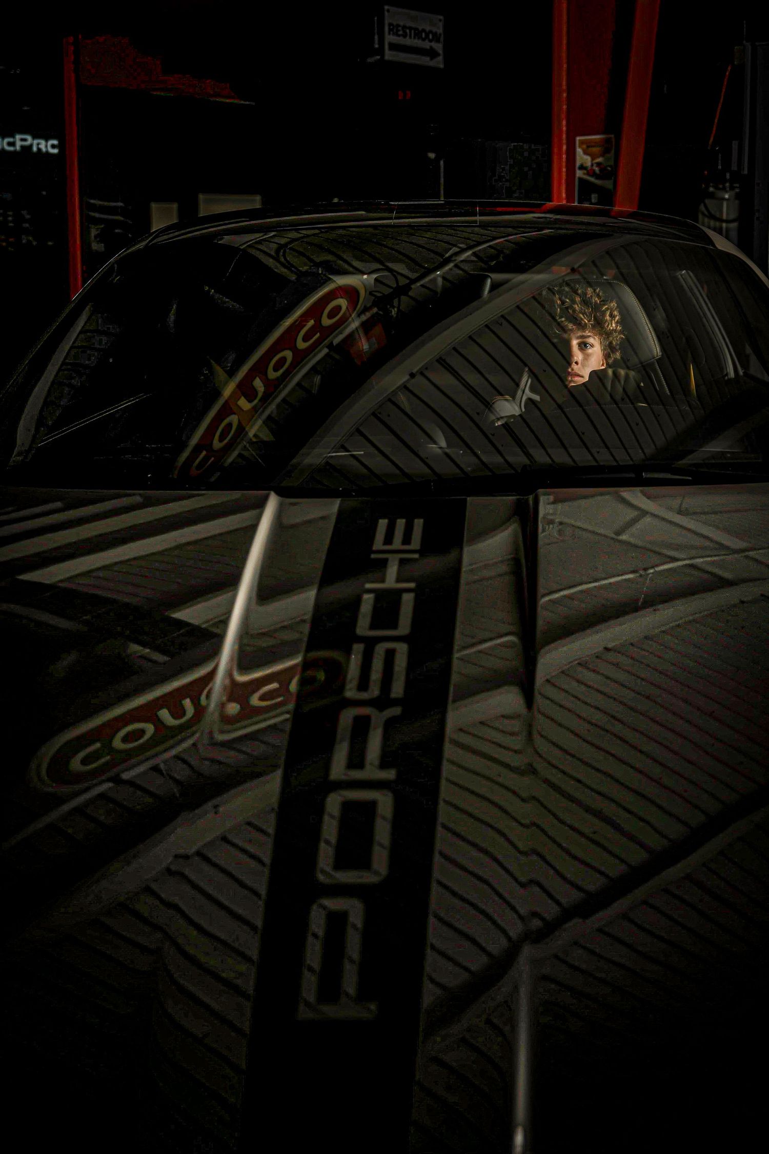 Dark car exterior with Porsche branding details and decals illuminated in dramatic low light conditions.