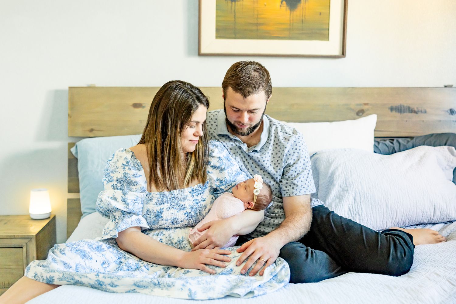 Parents snuggle on their bed holding their new baby girl during newborn photos in Colorado Springs.