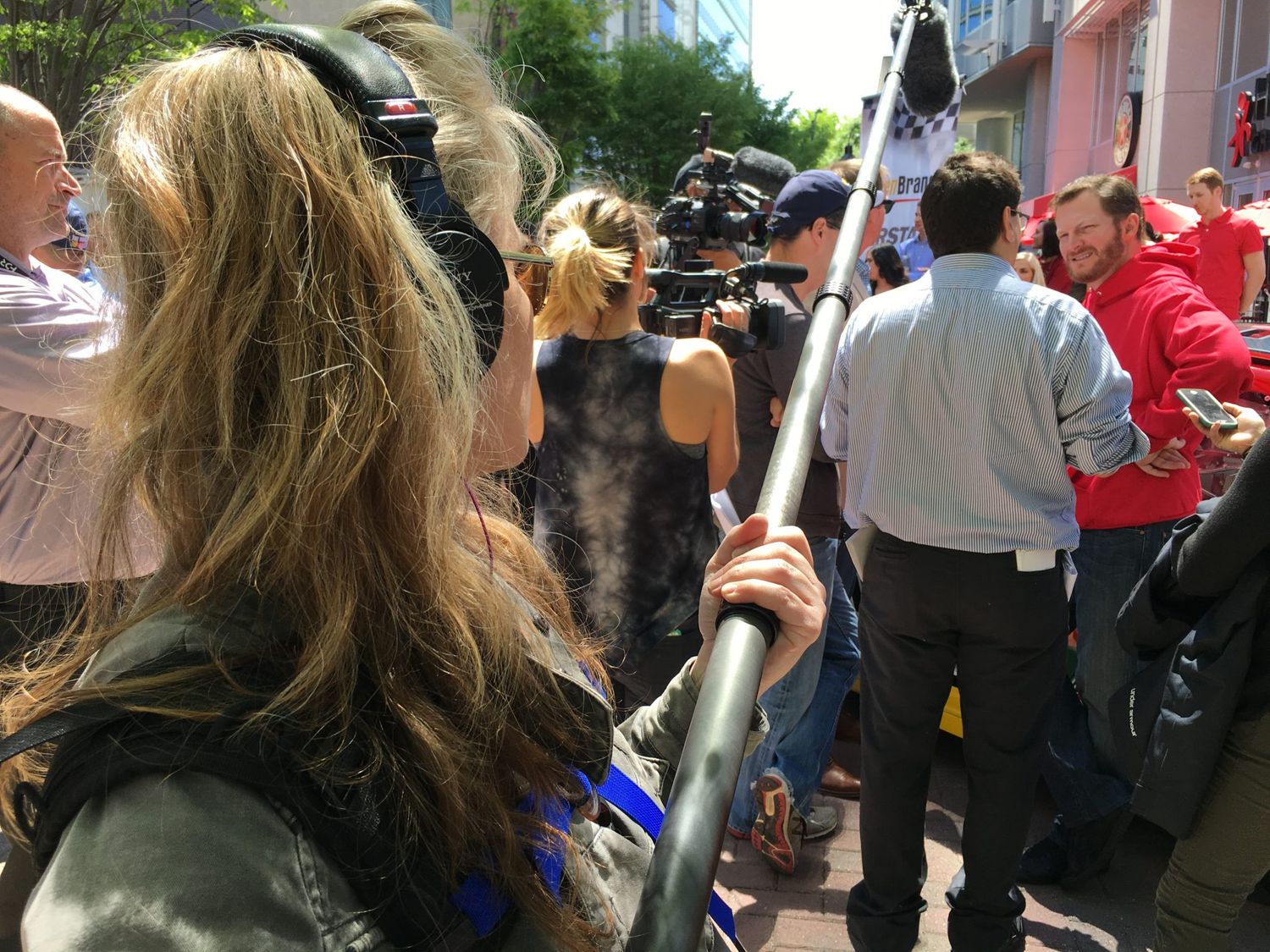 Media crew with cameras and audio equipment follow a crowd during a news event.