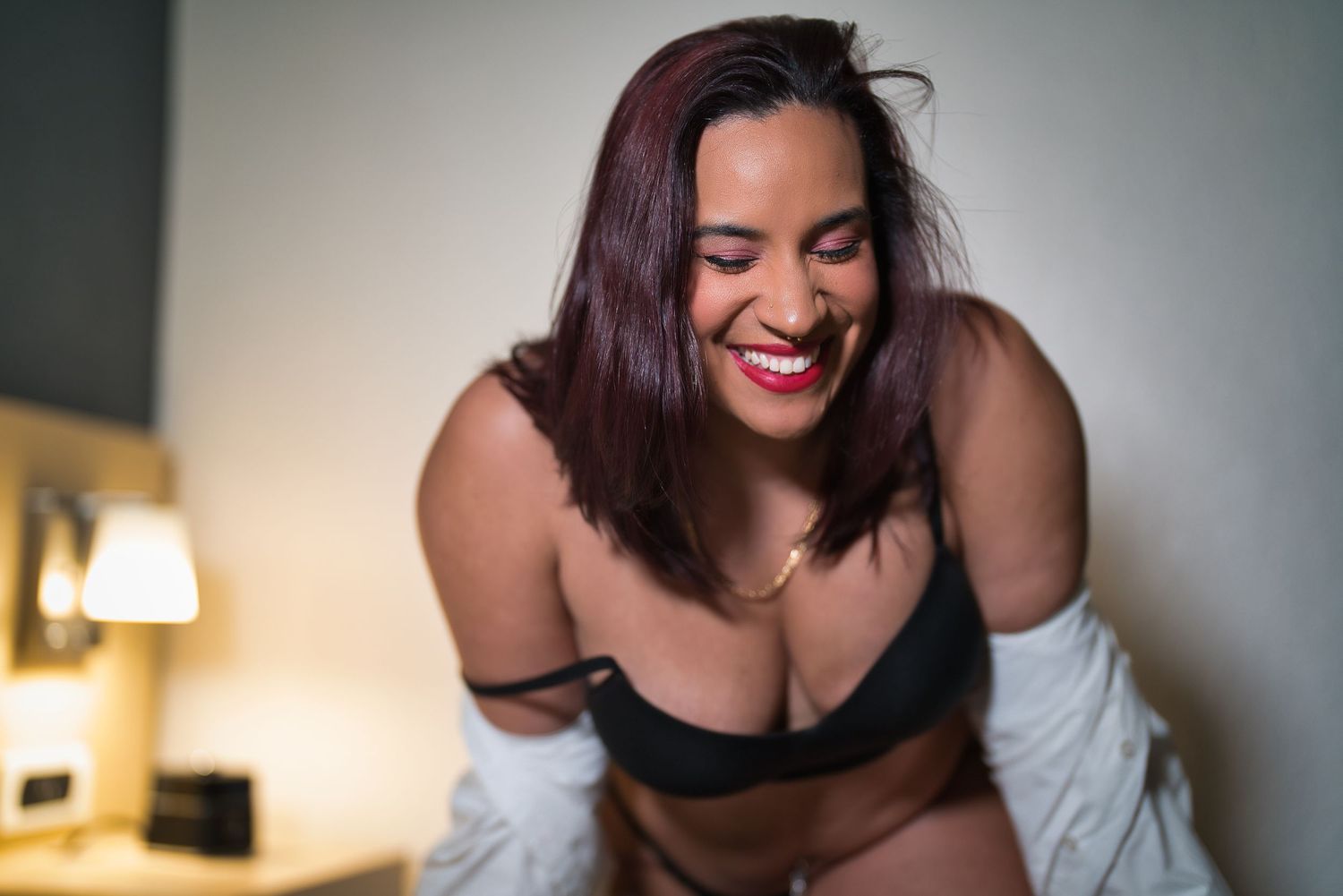 A boudoir photography session featuring intimate poses in a dimly lit bedroom setting.