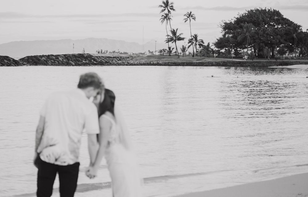 A black and white beach wedding photo with palm trees and ocean views.