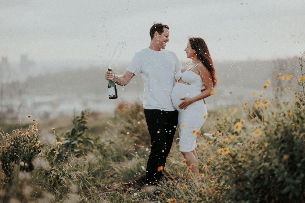 A couple shares a playful moment on a hilltop during sunset.