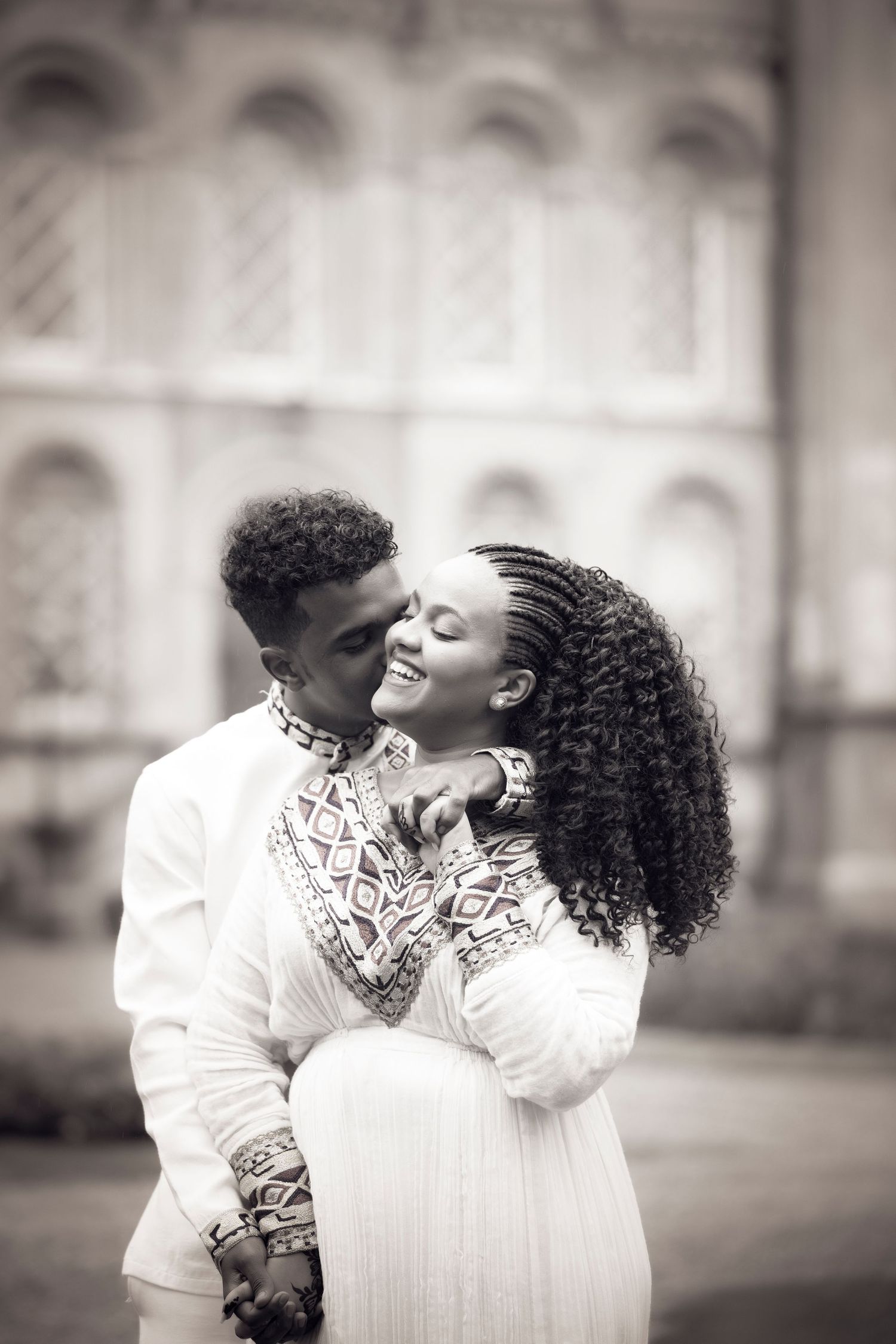 Romantic black and white portrait of couple in matching white outfits.