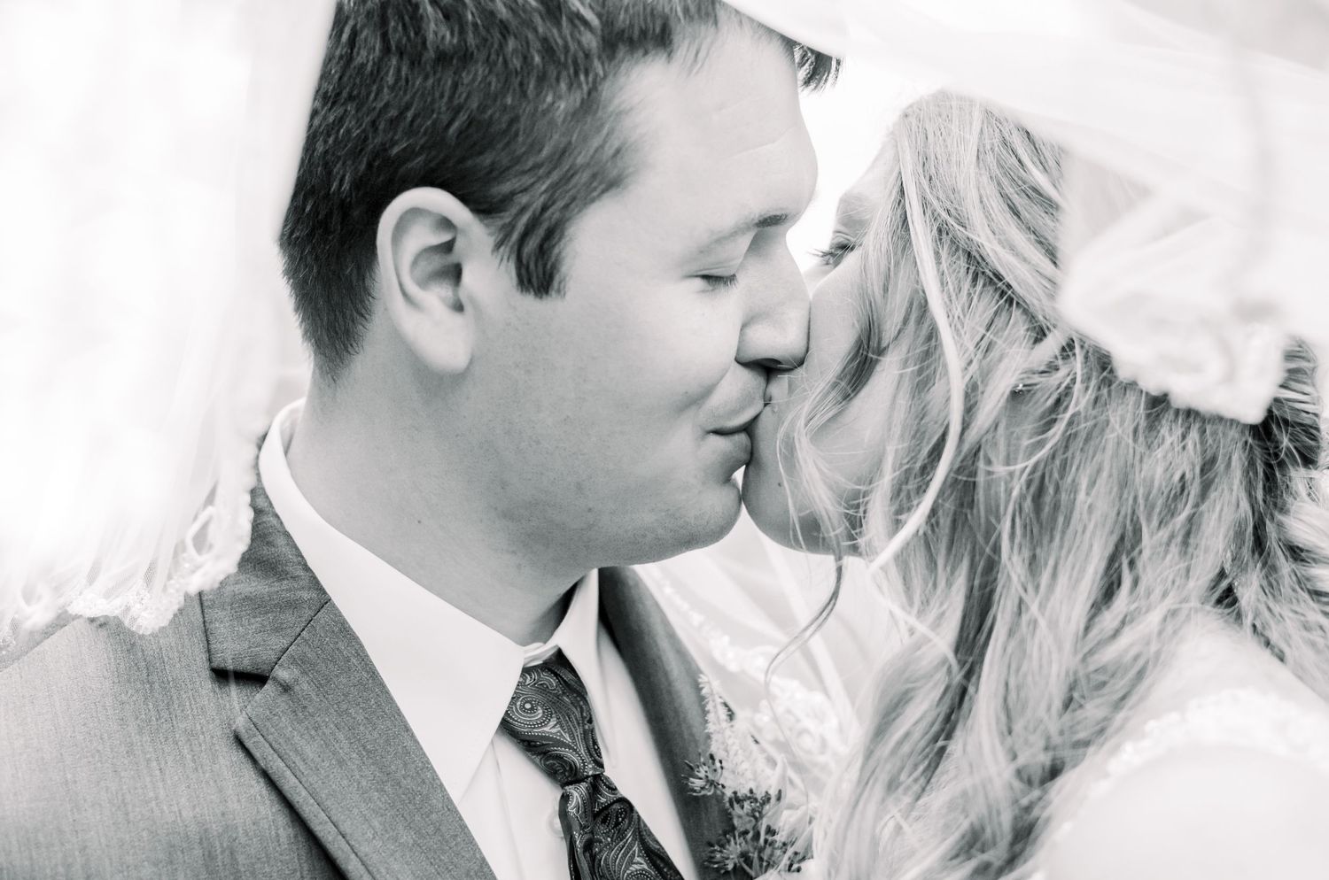 Romantic wedding couple shares an intimate moment in black and white photography.