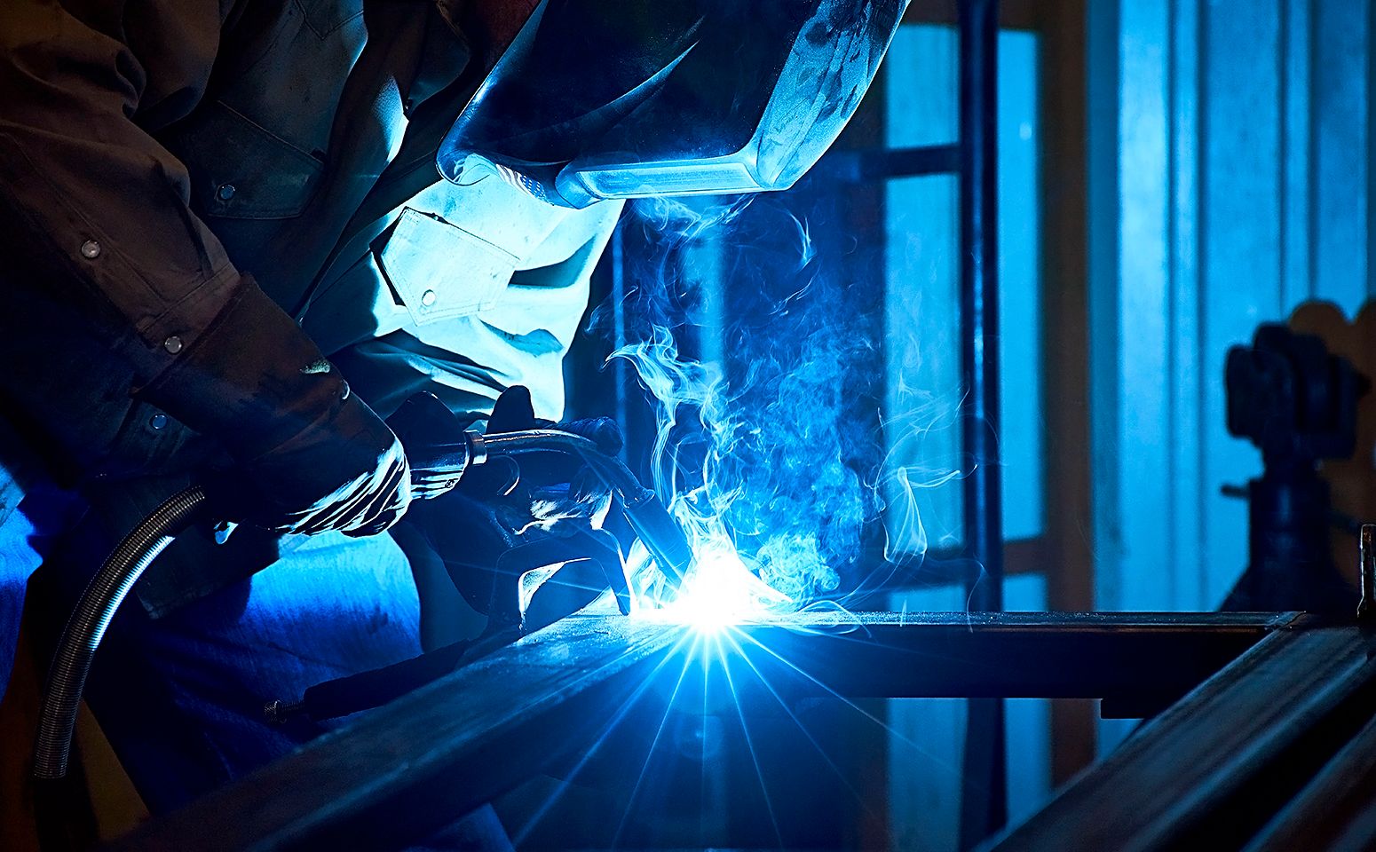 Oil and gas worker welding pipe with blue flame