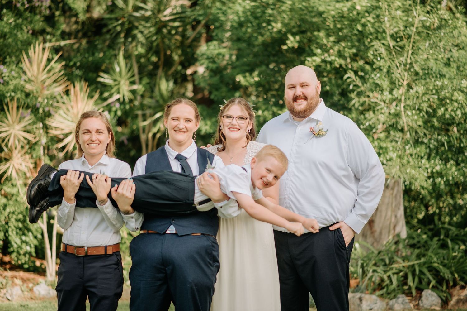 Group poses joyfully in a garden setting during a celebration.
