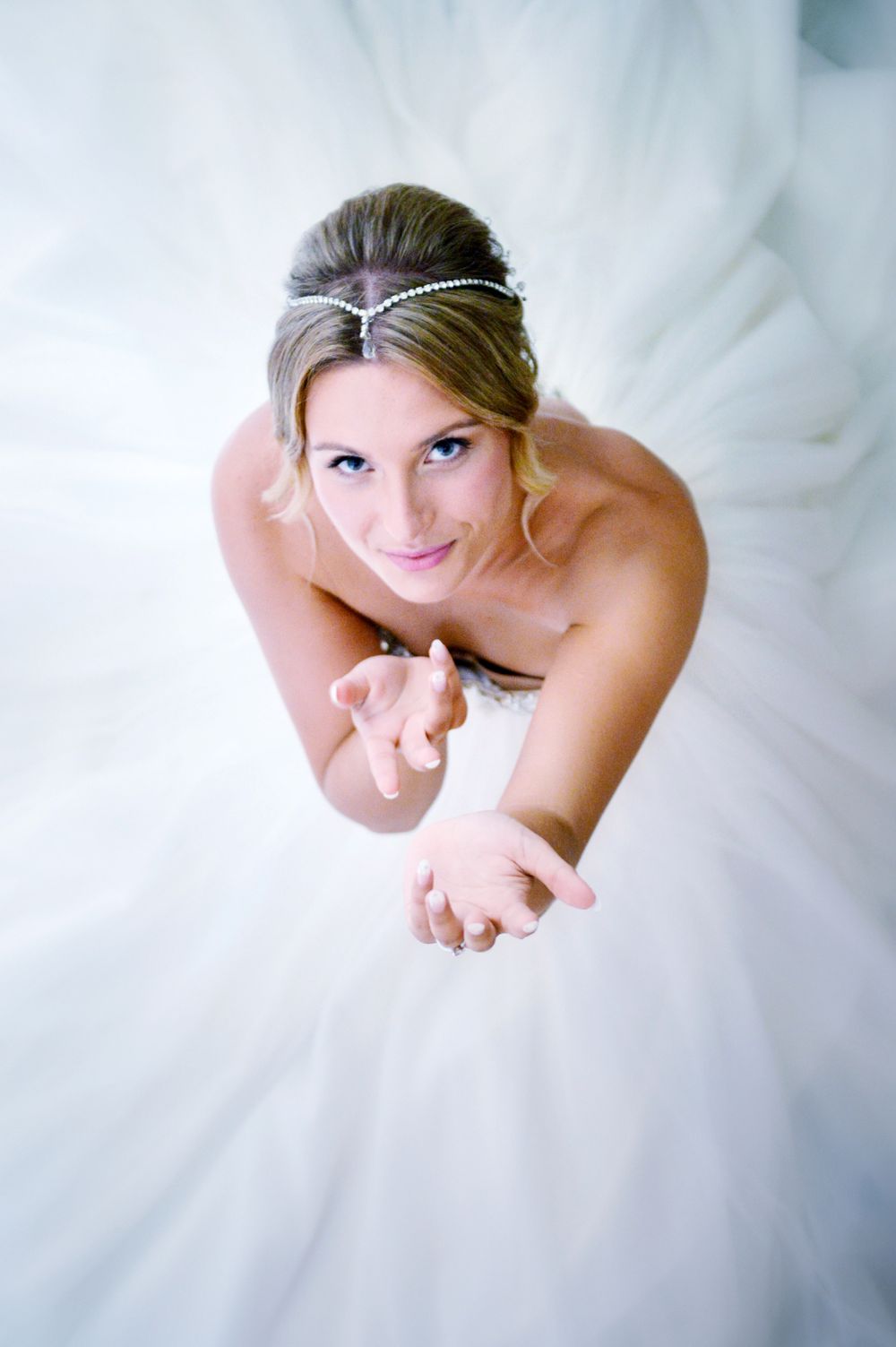 Overhead view of a bride in a classic white ball gown with crystal headpiece against flowing tulle.