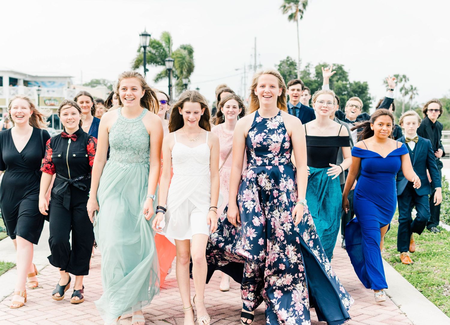 Group of people in formal attire walking together at outdoor event.