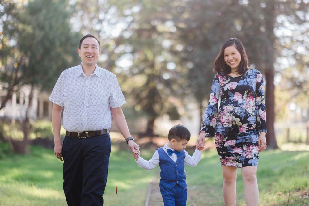 A family walks hand in hand through a sunny park on a spring day.