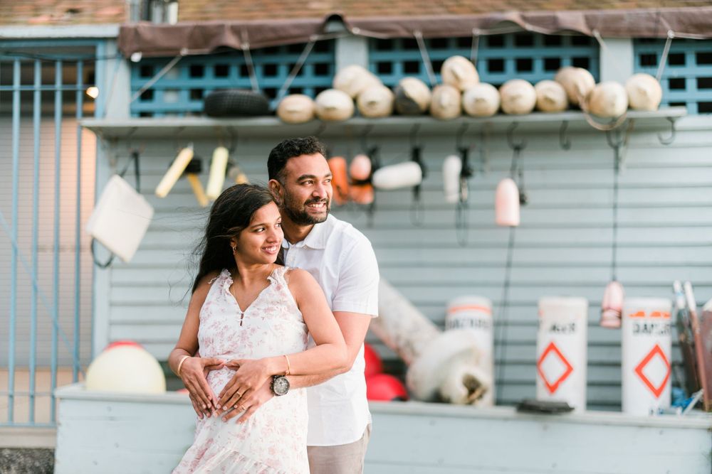 A couple embraces in front of a rustic building with decorative lanterns.