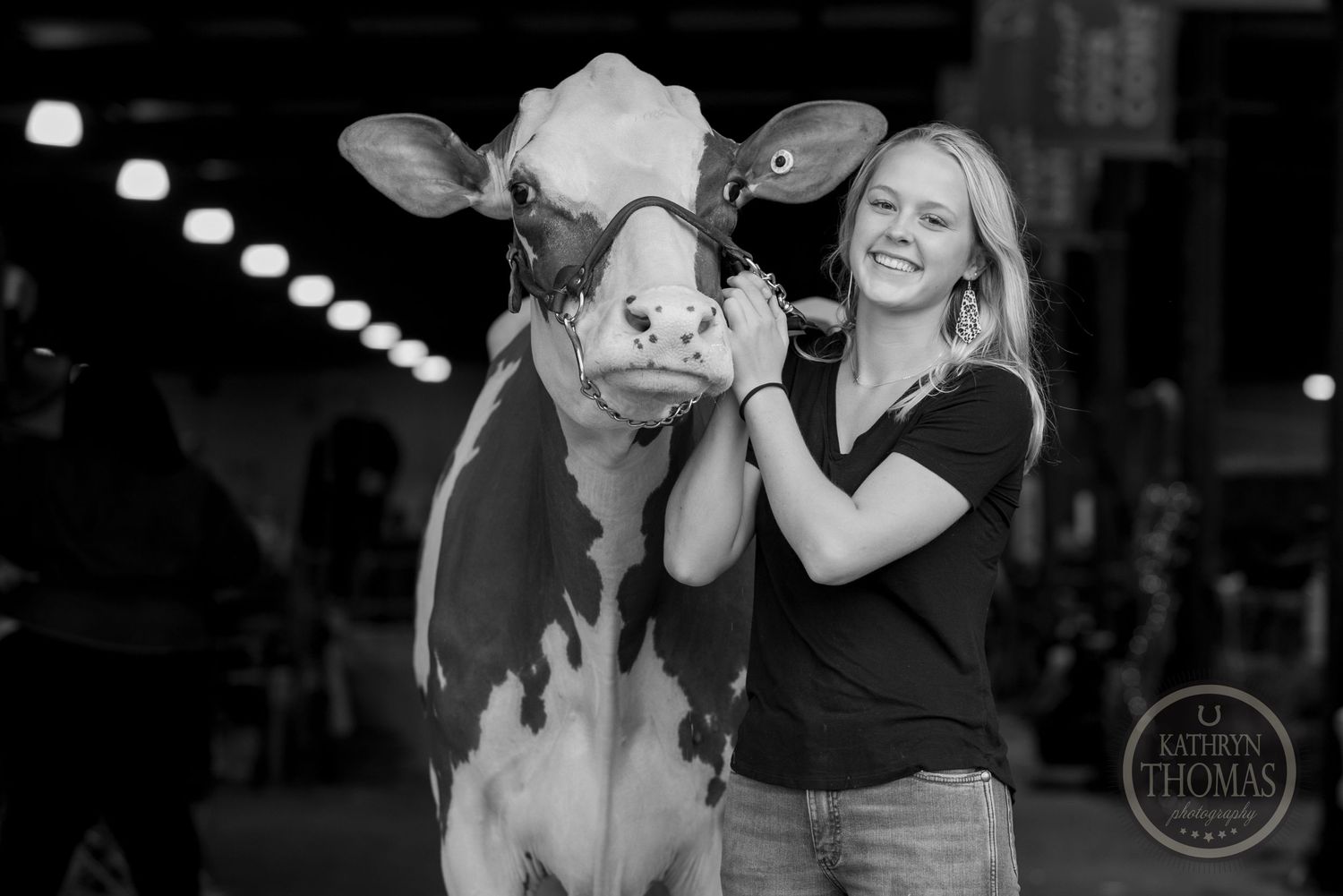 A black and white portrait of a dairy cow and handler sharing a playful moment at a show.