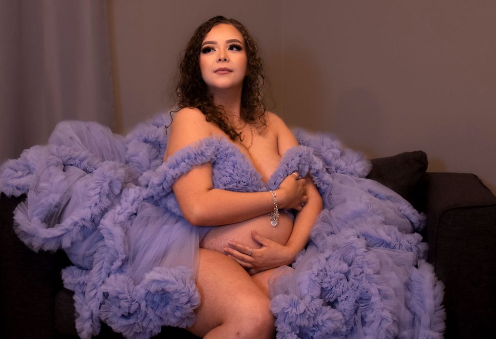 A boudoir photoshoot featuring a lavender tulle dress against a dark background.