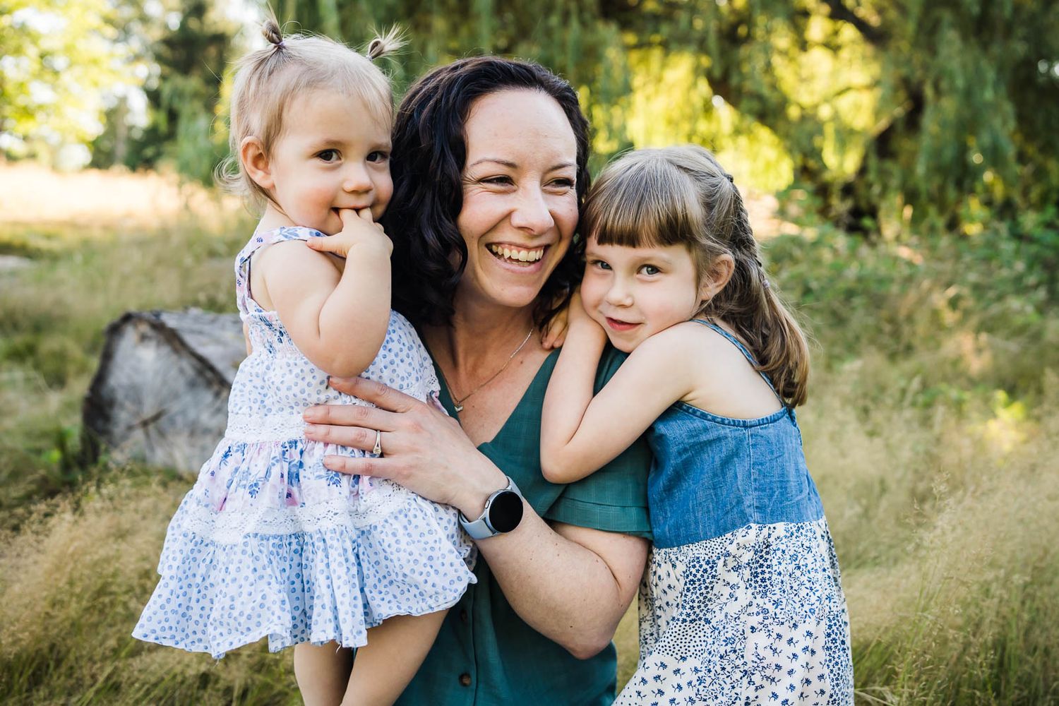Candid photo of mother snuggling with her daughters in Kirkland.