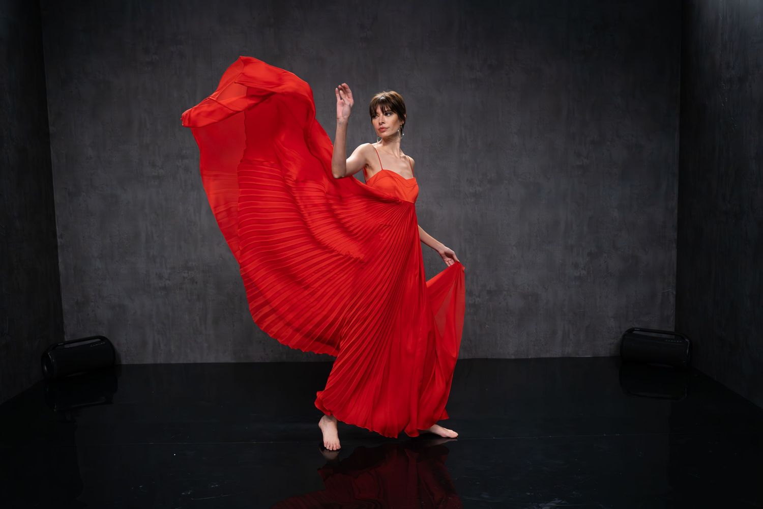 Dramatic dance performance in flowing red dress against dark background.