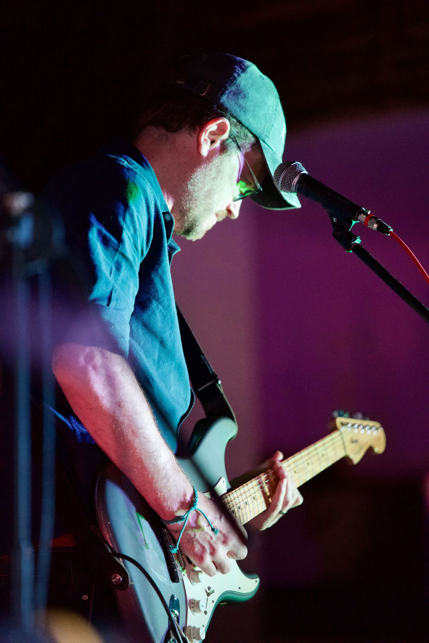 Guitarist performing on stage under blue stage lighting.