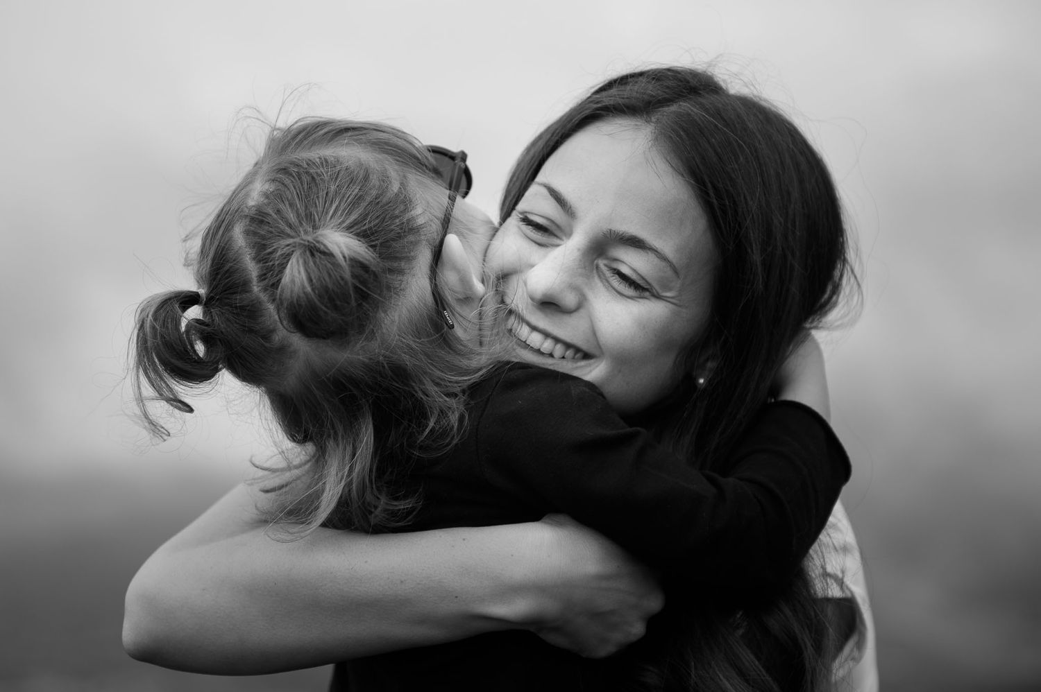 Black and white intimate moment of loving embrace between parent and child.