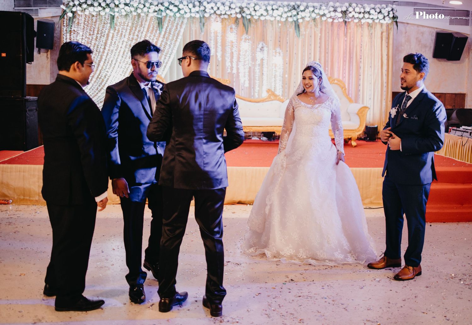 Wedding party members gathered in formal attire at an elegantly decorated reception venue.