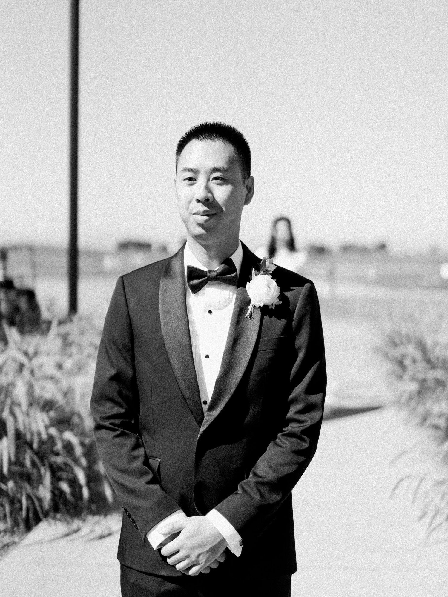 Formal black and white portrait of a groom in tuxedo with boutonniere.