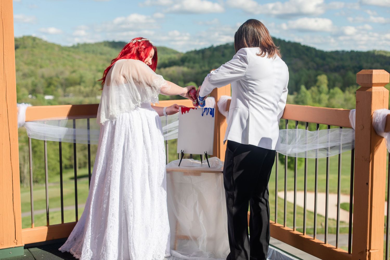 Wedding couple shares an intimate moment on an outdoor deck overlooking rolling green hills on their special day.