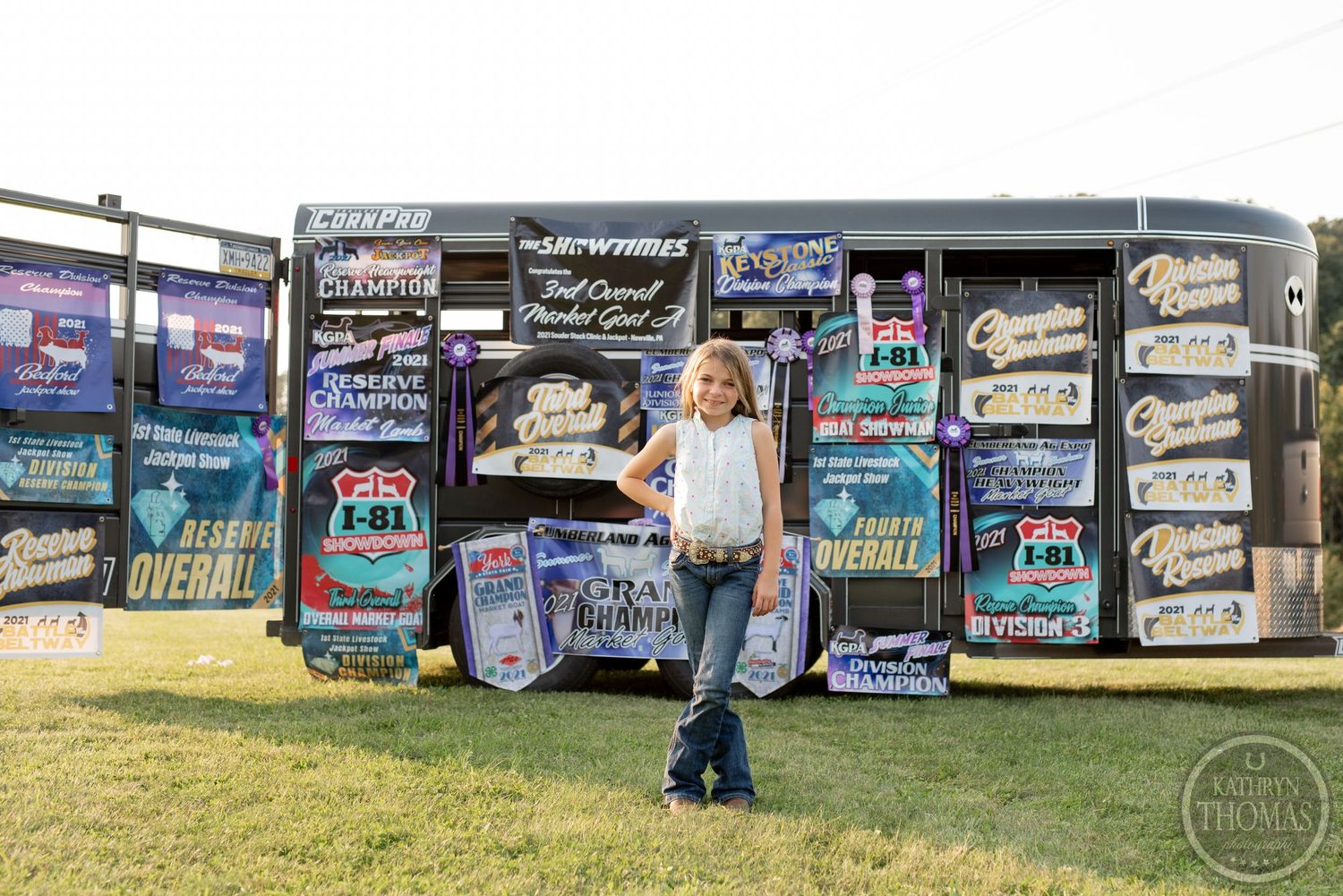 Person poses against wall of competition banners in casual western attire.