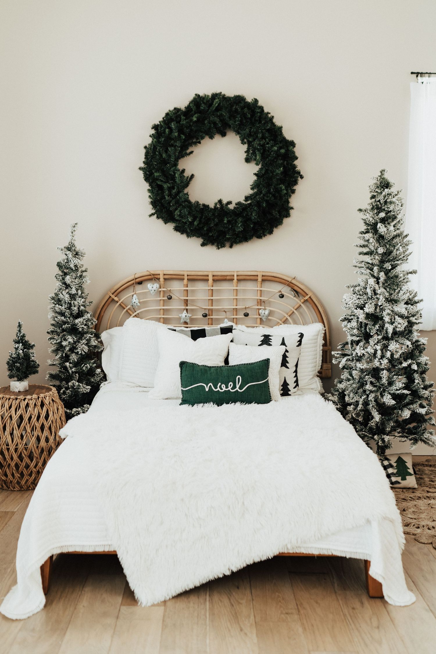 Minimalist Christmas bedroom with flocked trees, a wicker headboard, and a wreath above.