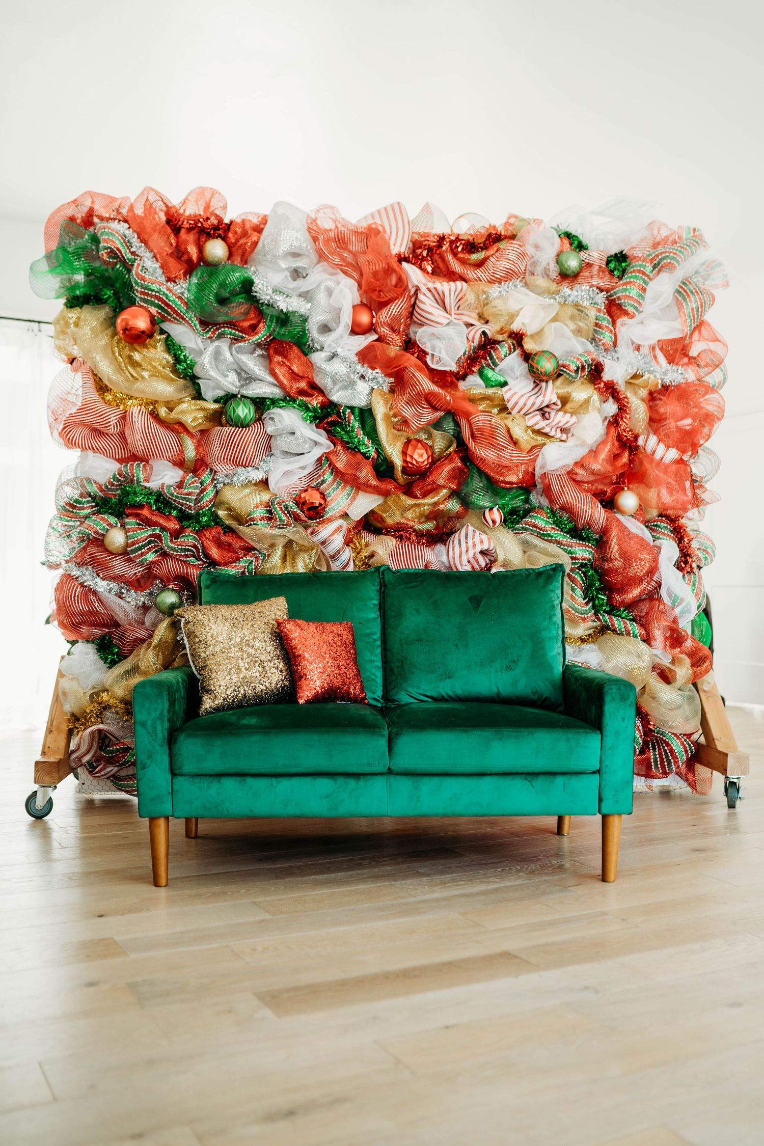 Emerald green velvet sofa against a vibrant coral and white floral backdrop.