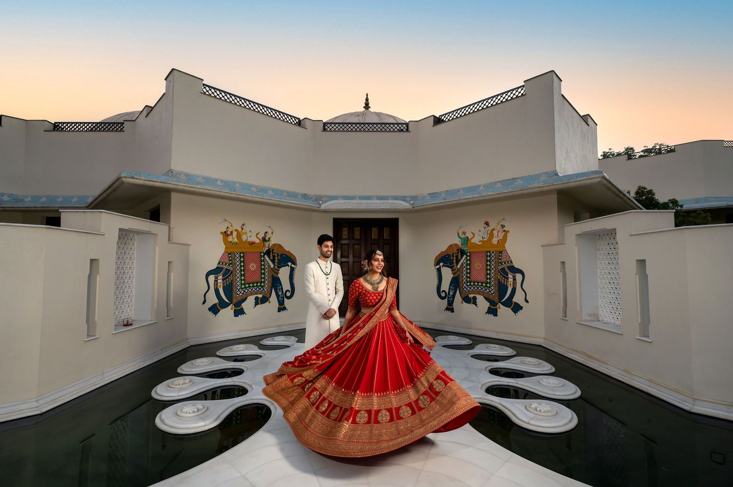 Indian destination wedding couple at a Rajasthan palace, bride in red lehenga at sunset Foto Collective photography.