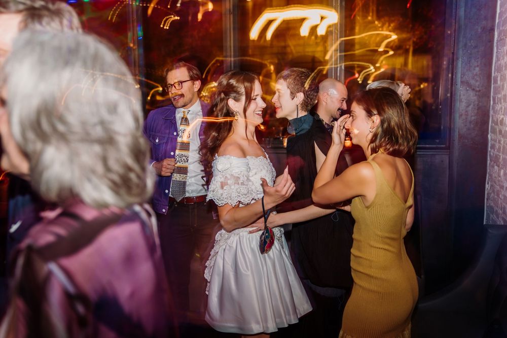 Wedding party dances and celebrates on a dimly lit dance floor during an evening reception.