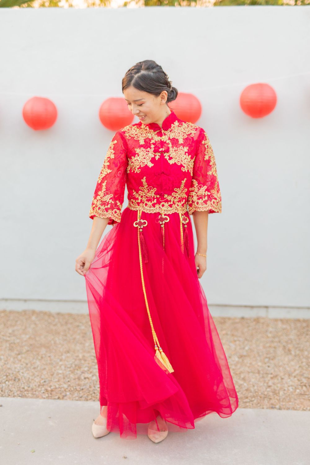 A woman wearing a traditional red Chinese wedding dress with gold embroidery details.