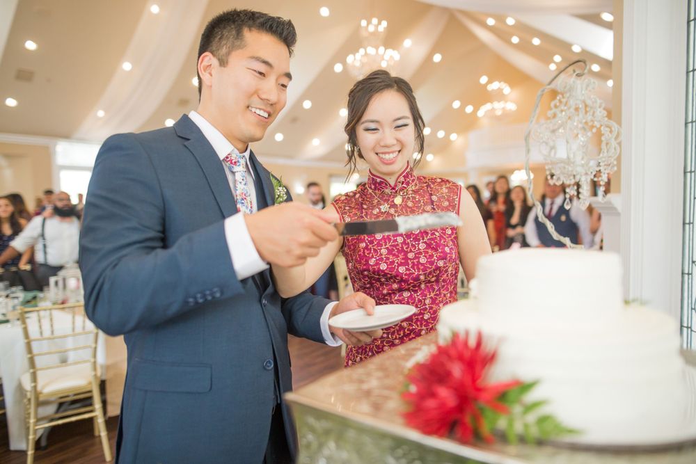 A couple celebrates with their wedding cake at an elegant indoor reception.