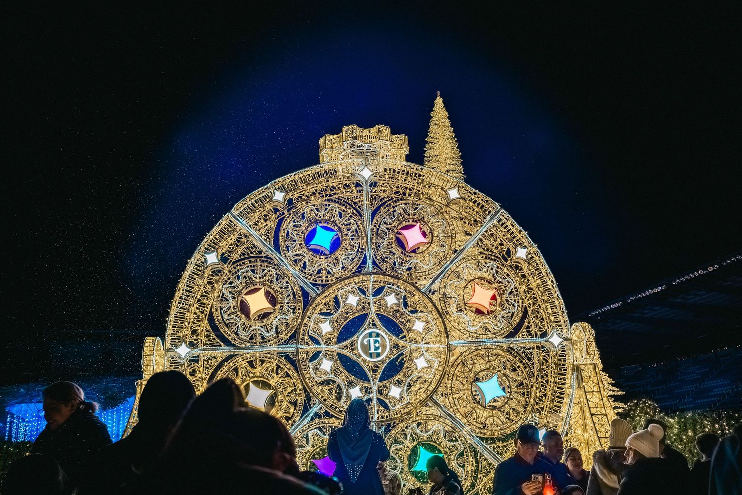 Ornate golden illuminated Christmas display with jewel-toned lights creating a magical atmosphere.