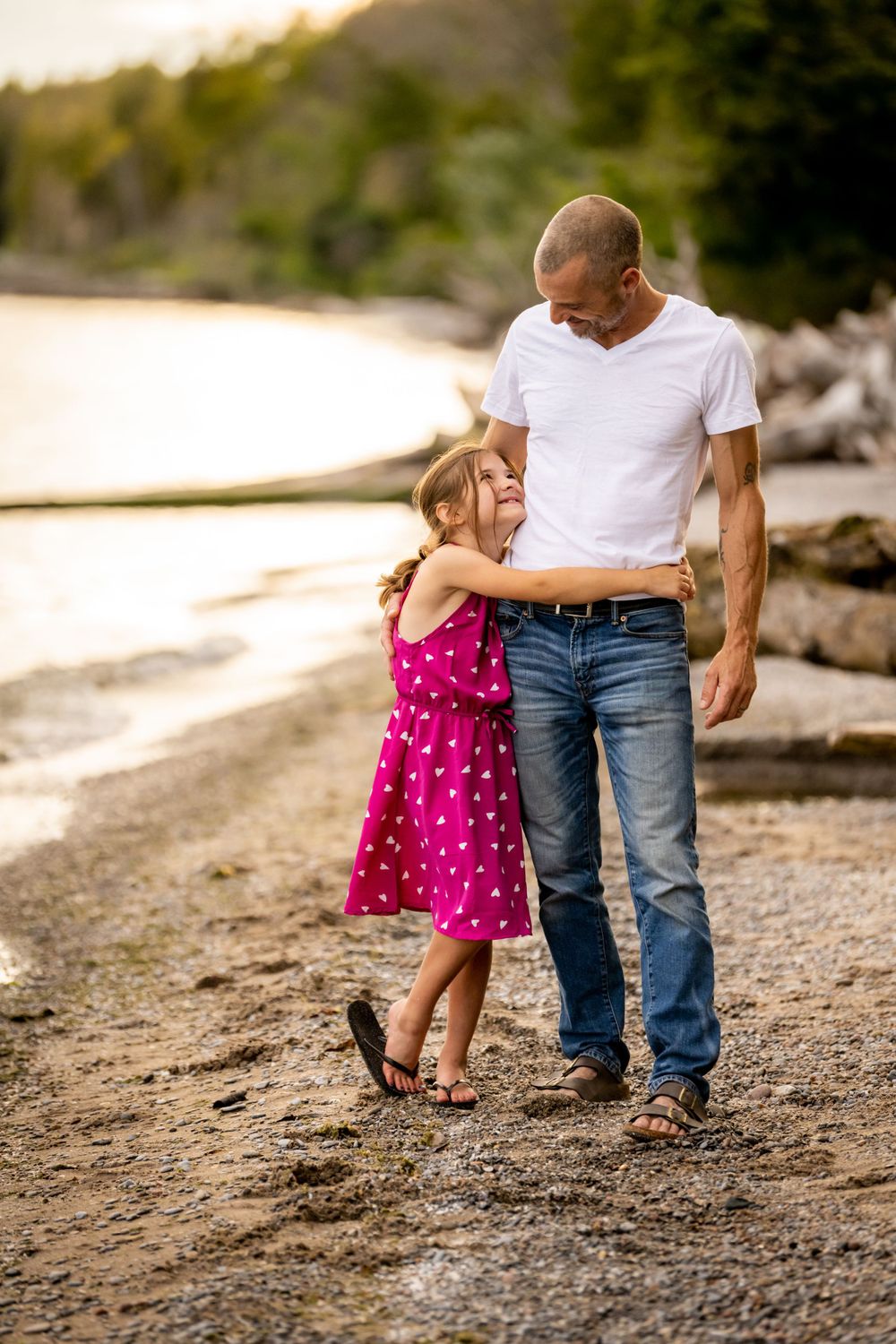 Sweet moment between parent and child hugging on rocky beach at sunset.