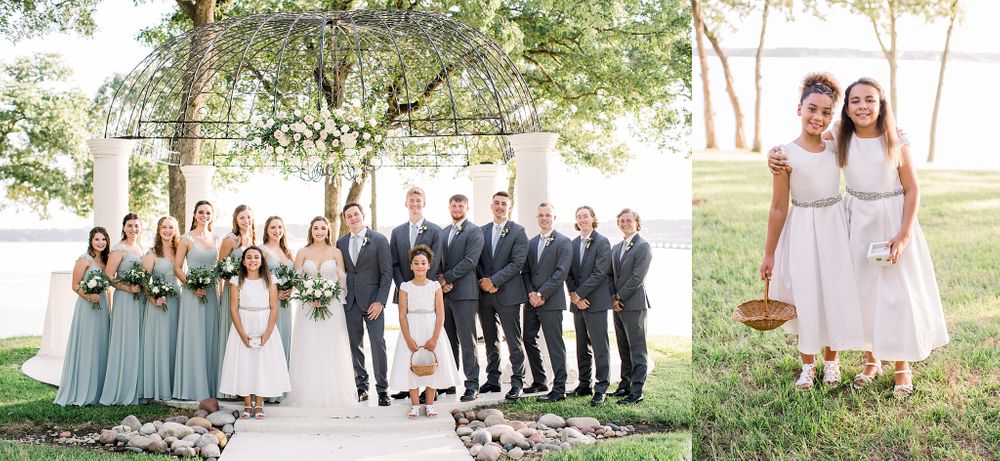 Wedding party poses in sage green and navy attire on a scenic waterfront.