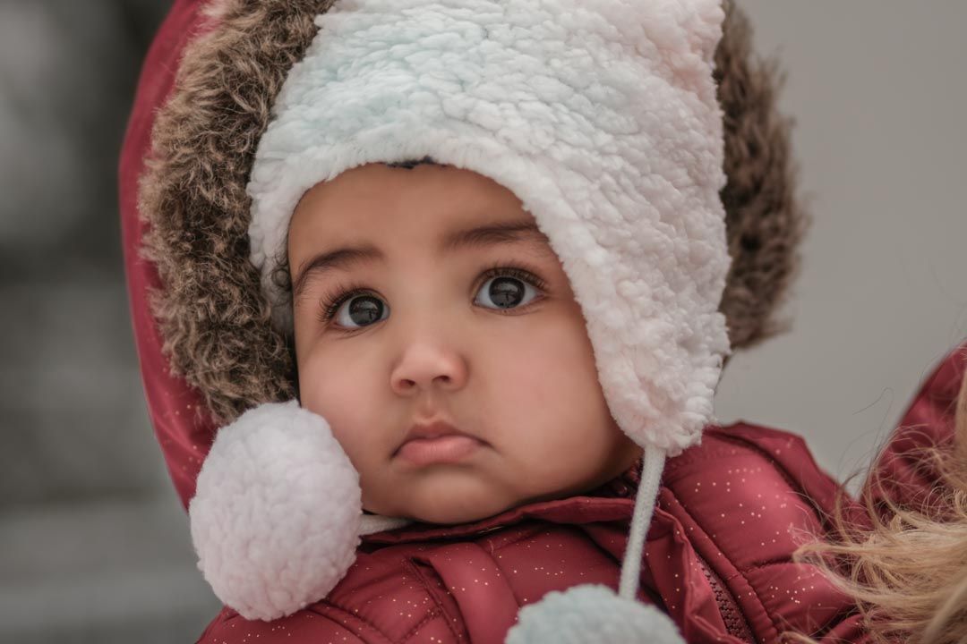 Toddler wearing Red snow jacket and white hat