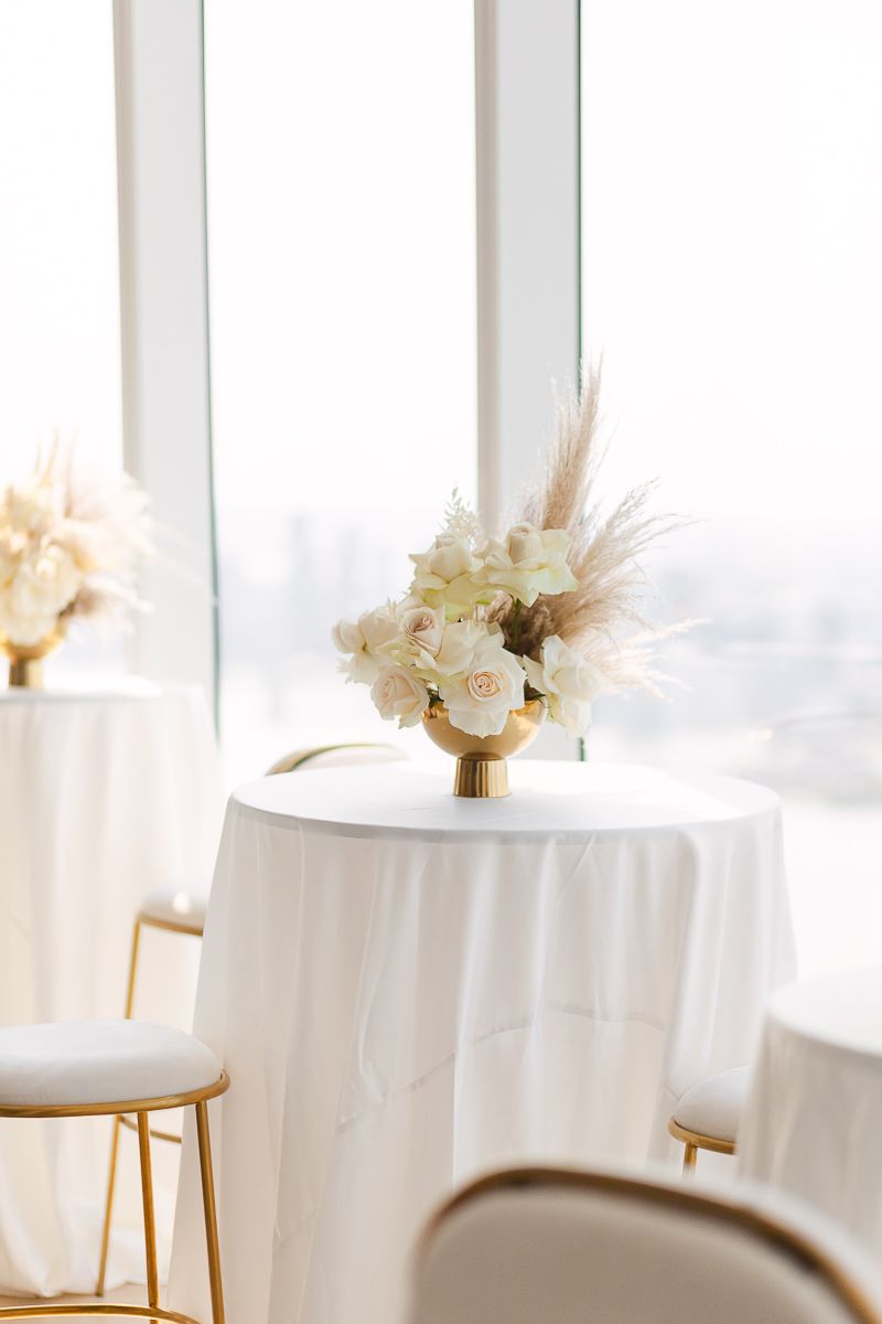 a cocktail table in white with a white roses floral arrangement on a gold vase at Hudson Yards by Paula Ortiz NY Family
