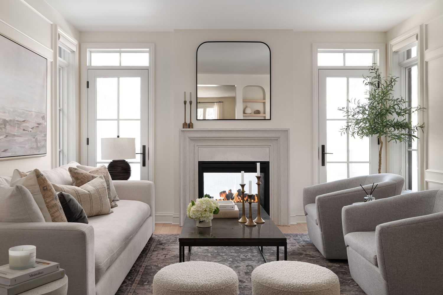 Elegant living room with fireplace, arched mirror, and symmetrical gray seating arrangement.